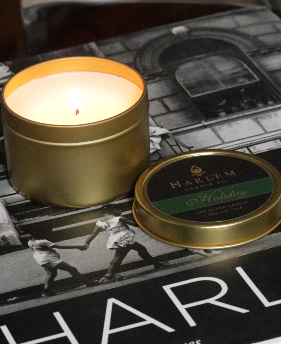 Gold candle tin with a lit candle on a black and white photo background