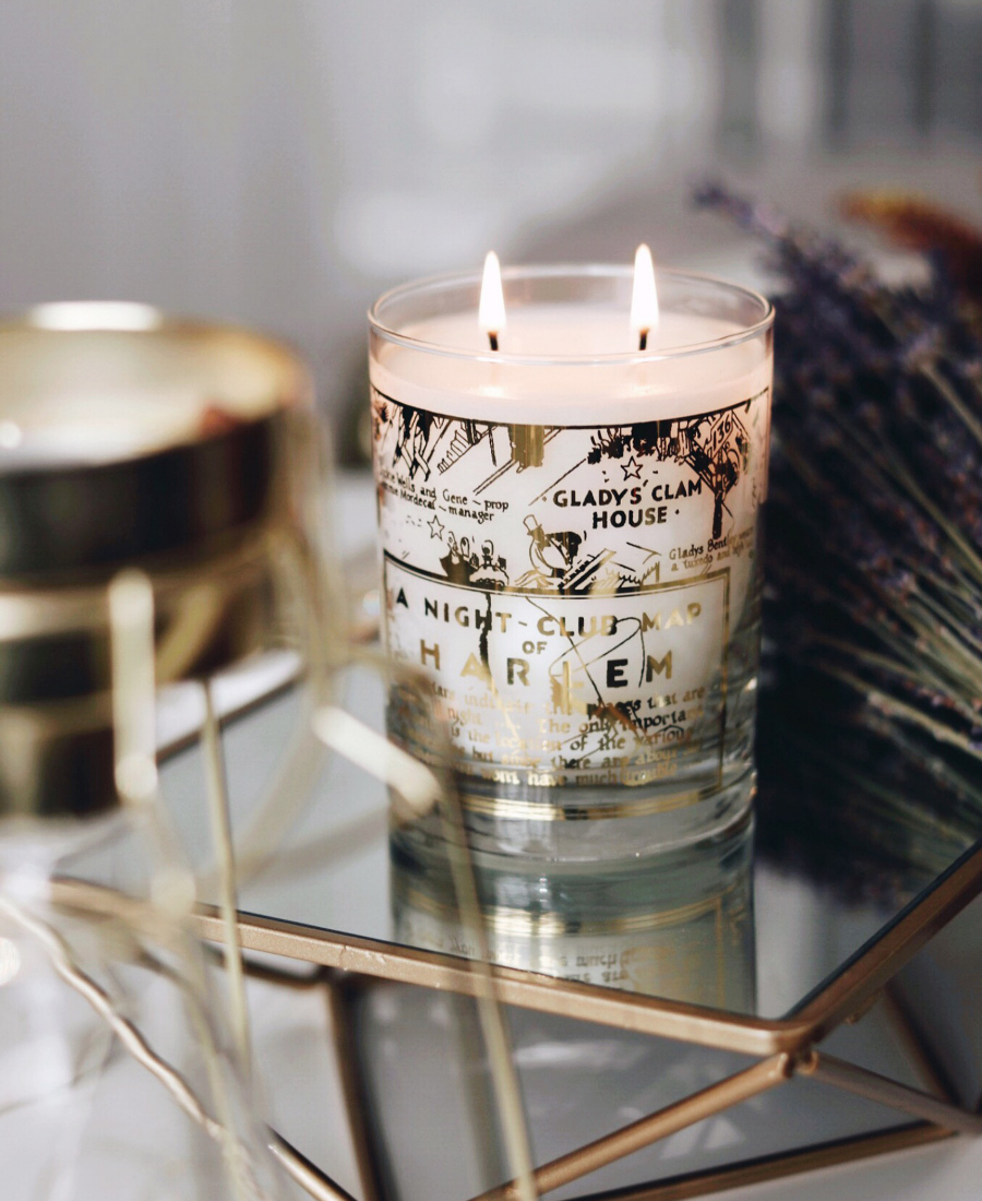 22k Gold Nightclub Map Savoy Candle on a reflective tray with flowers.