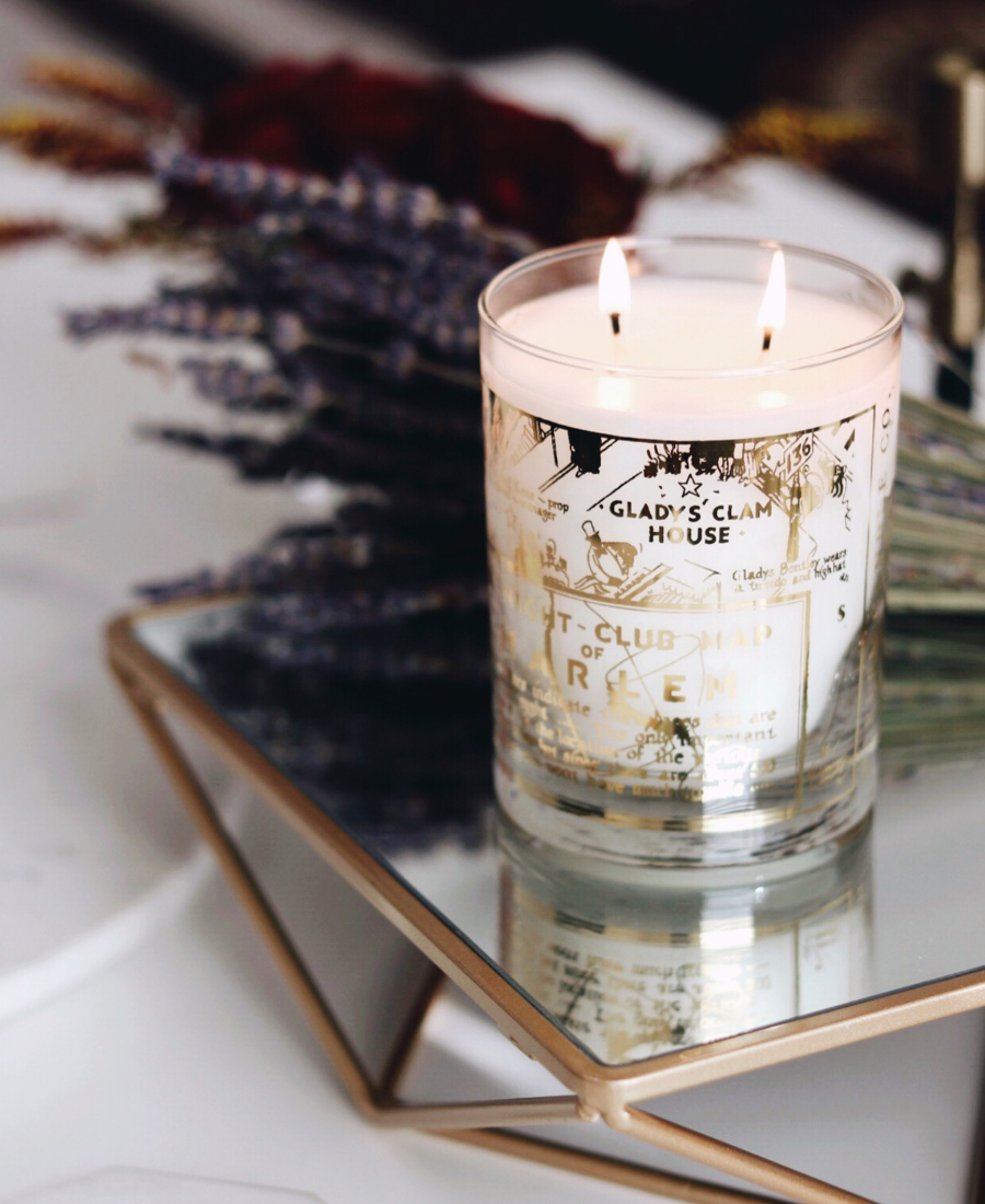 22k Gold Nightclub Map Savoy Candle on a reflective tray with flowers.