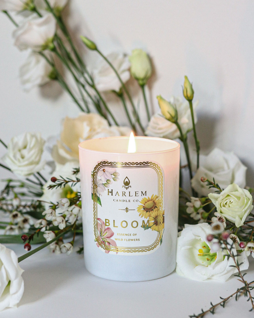 Bloom Candle on a white table with flowers.