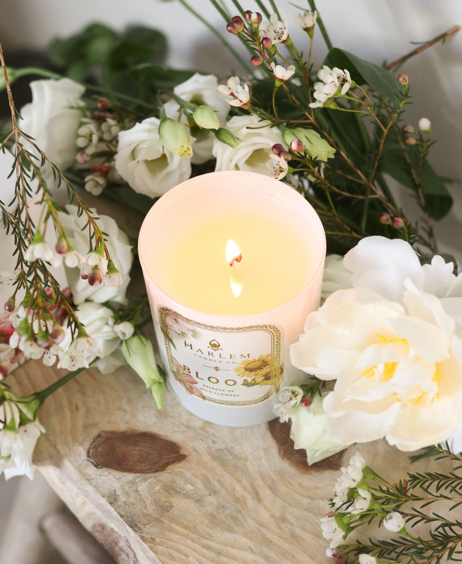 Bloom Candle on a wooden table with flowers.