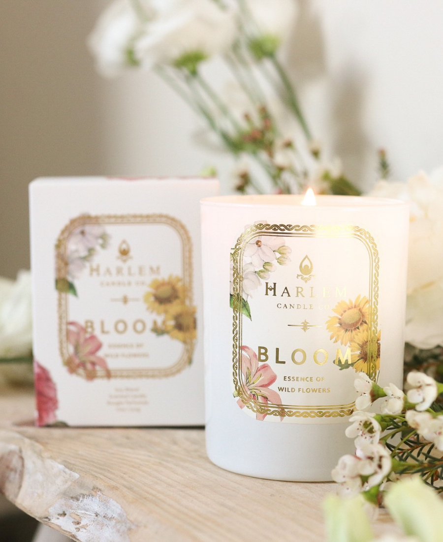 Bloom Candle and box on a wooden table with flowers.