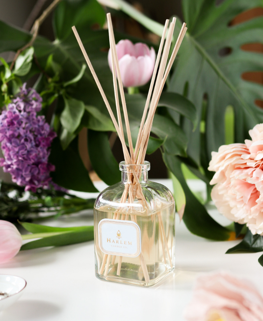 Joy Reed Diffuser on a white table with flowers.