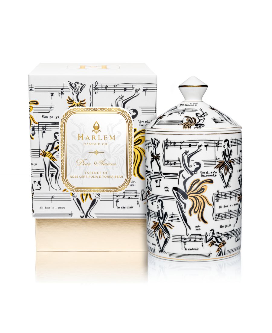 This is an image of our gold and white Deux Amours, ceramic candle with a lid. It features illustrations of Josephine Baker, and other original illustrations. This candle is featured next to its decorative box.