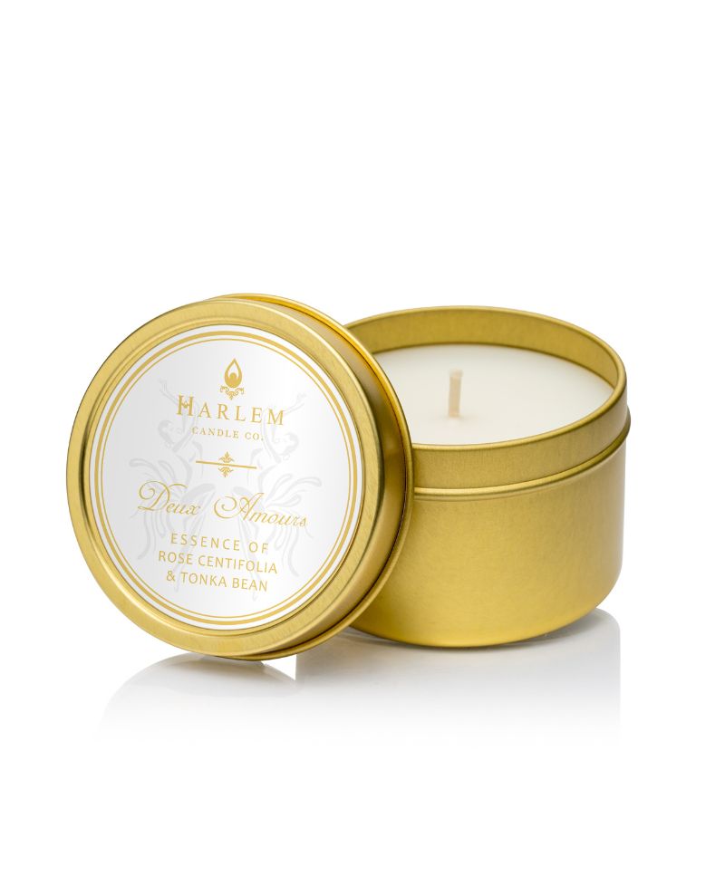 Picture of the Deux Amours Travel candle. It is in a gold tin with a white label with Josephine illistrations on the top.