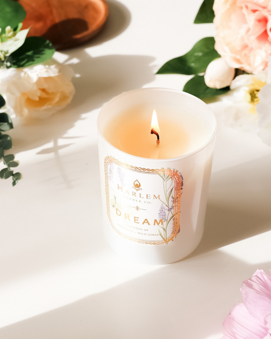 Dream Candle on a white table with flowers.