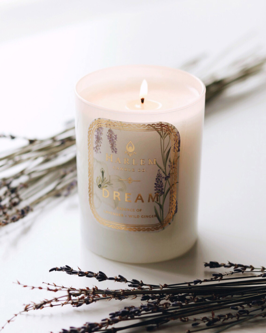 Dream Candle on a white table with flowers.
