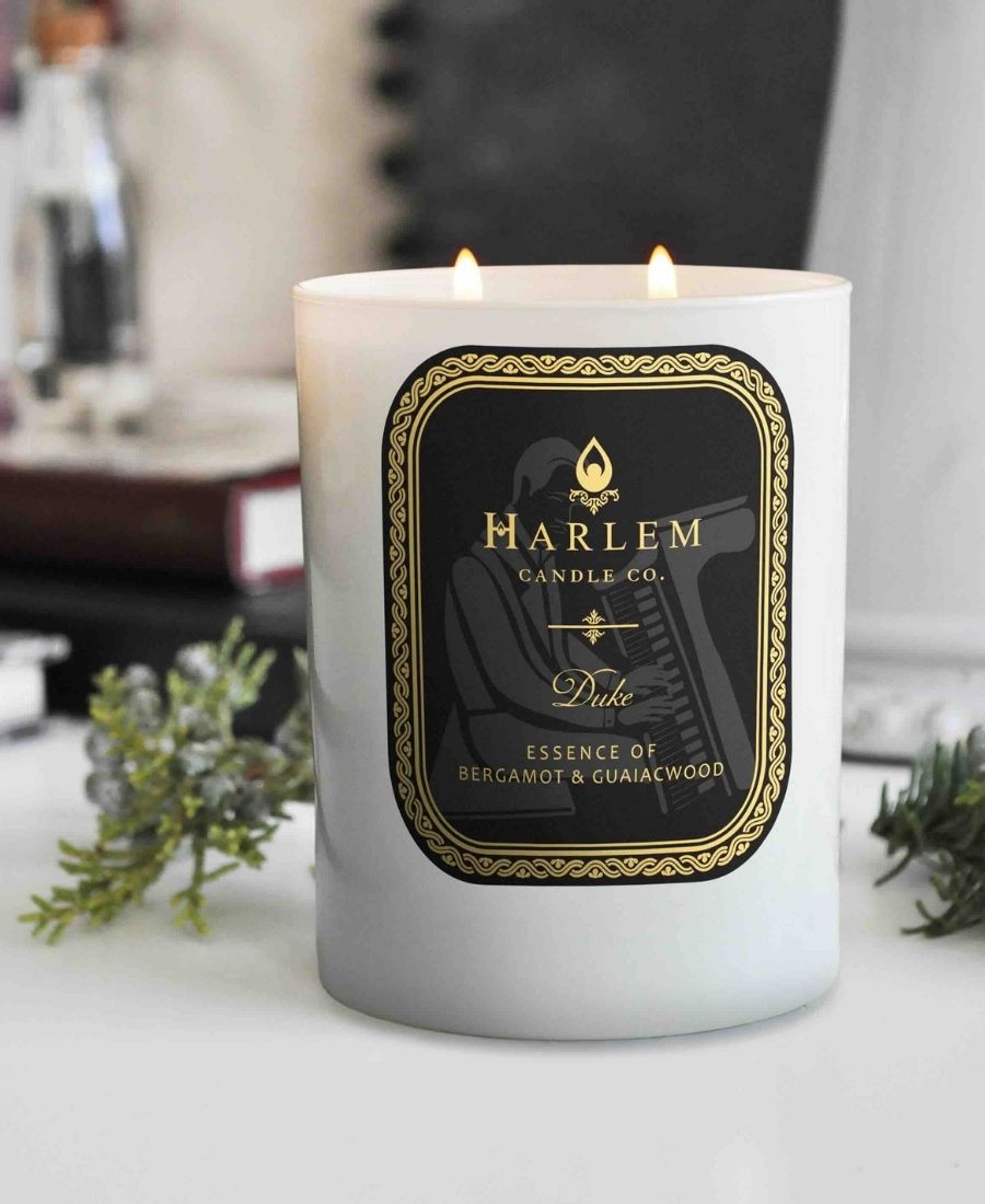 Duke Candle on a white table with greenery.