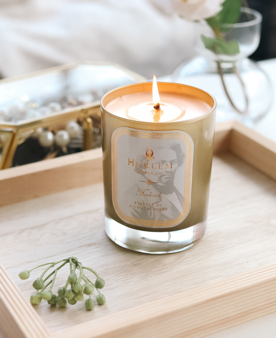 Frederick Candle on a wooden tray with jewelry and greenery.