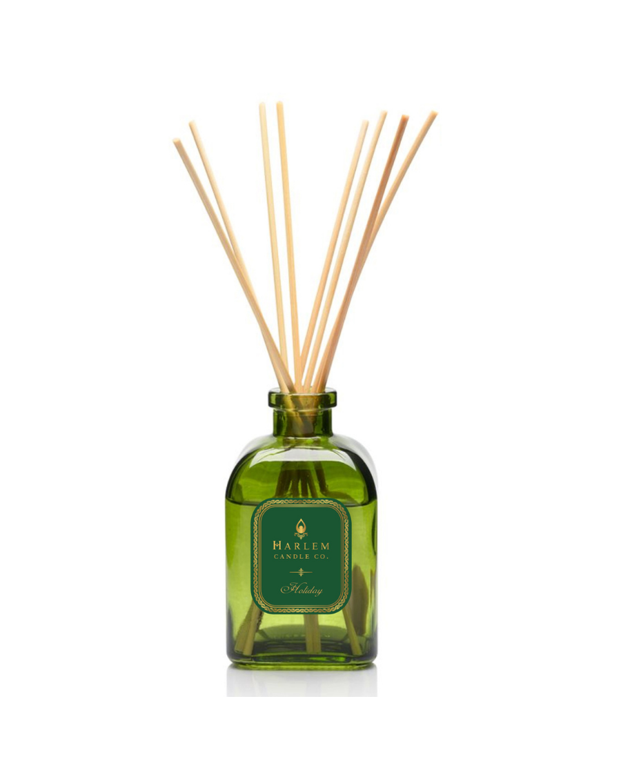 Holiday reed diffuser bottle with multiple natural wood reed sticks rising above the top, set against a plain white background.