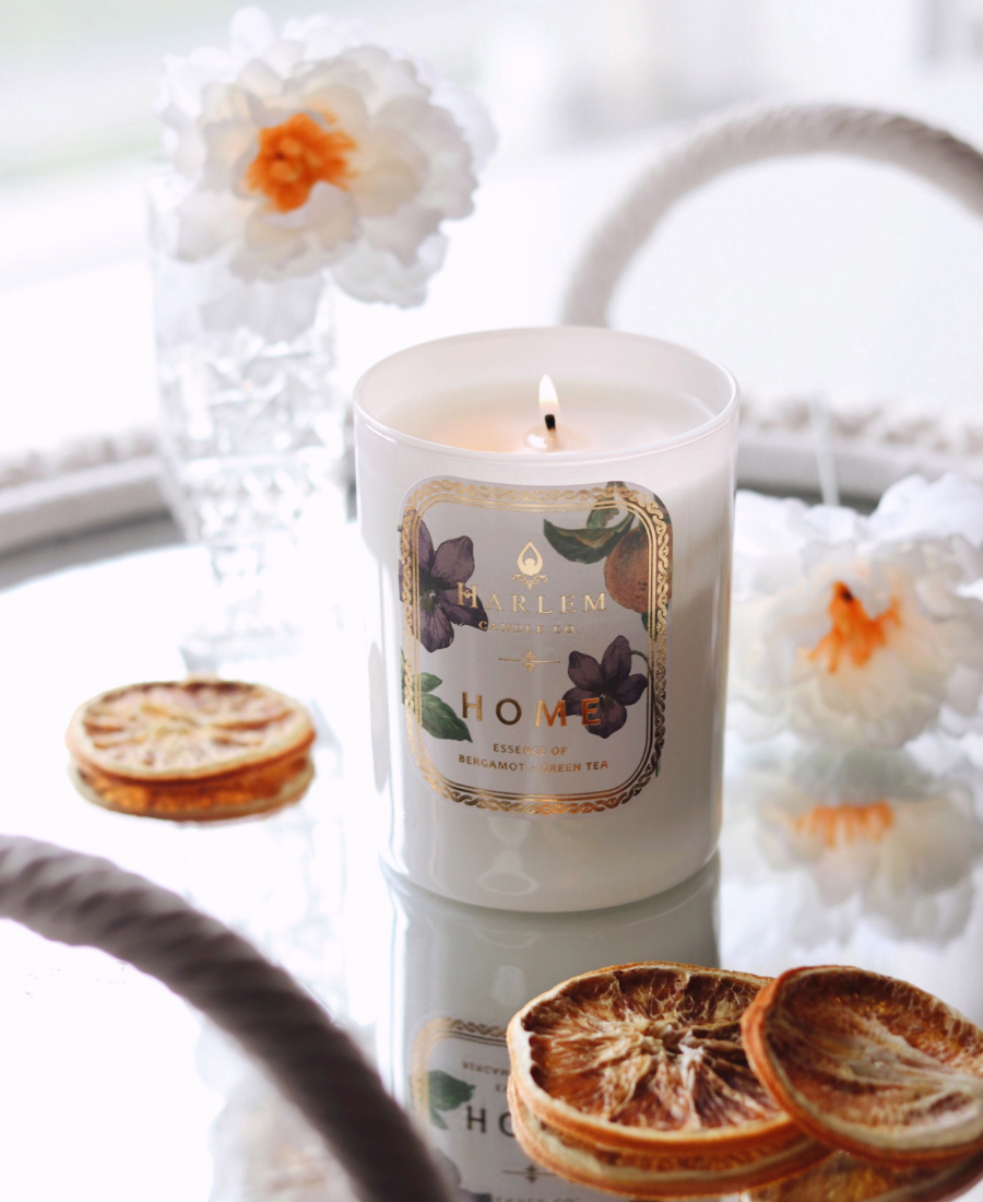 Home Candle on a reflective table with flowers, glassware, and dried orange slices.