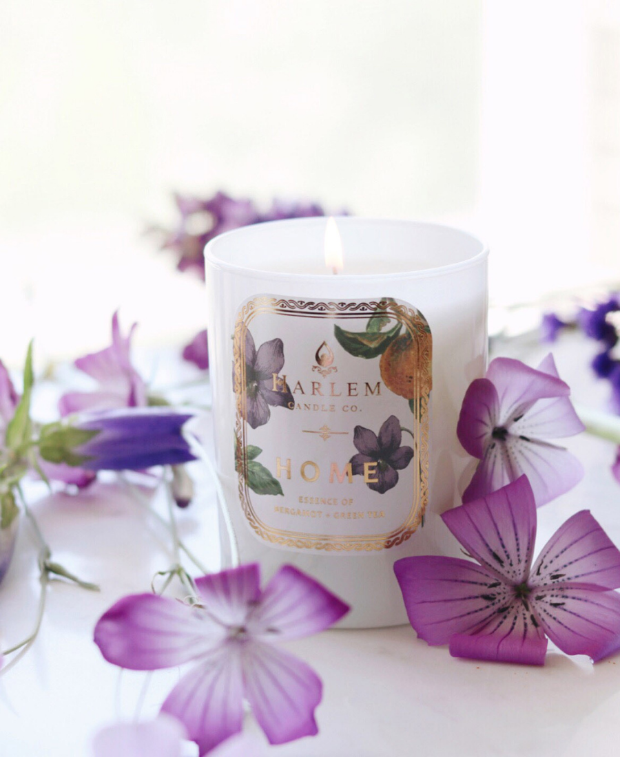 Home Candle on a white table with purple flowers.