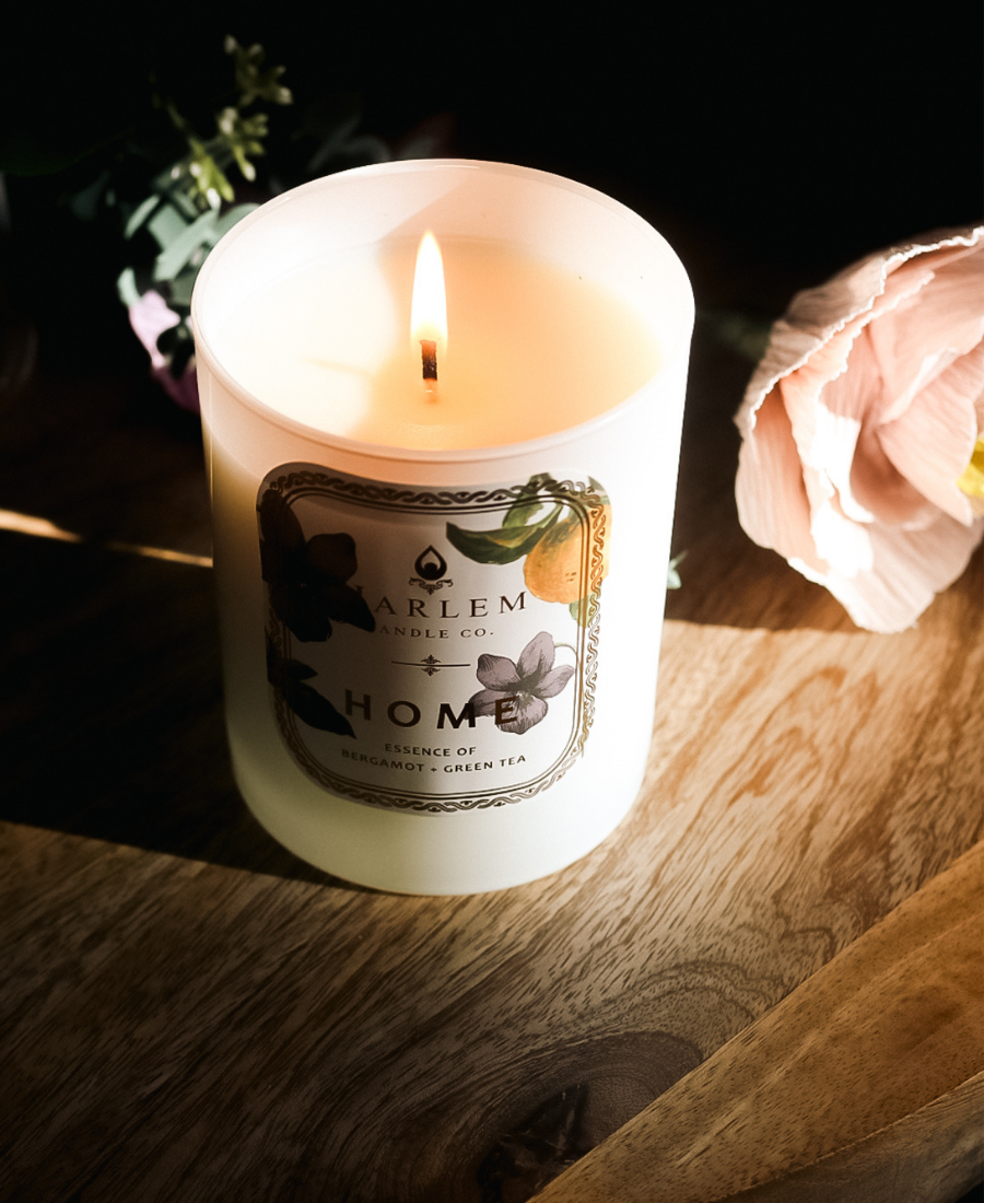 Home Candle glowing on a wooden table with flowers.