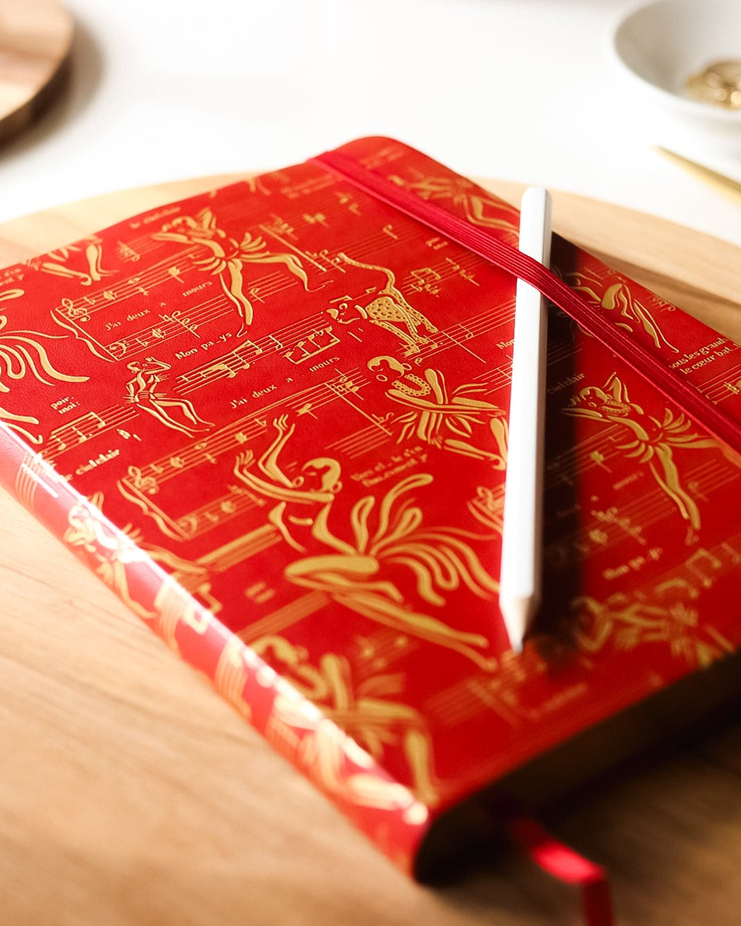 The red journal on a table with a pencil.