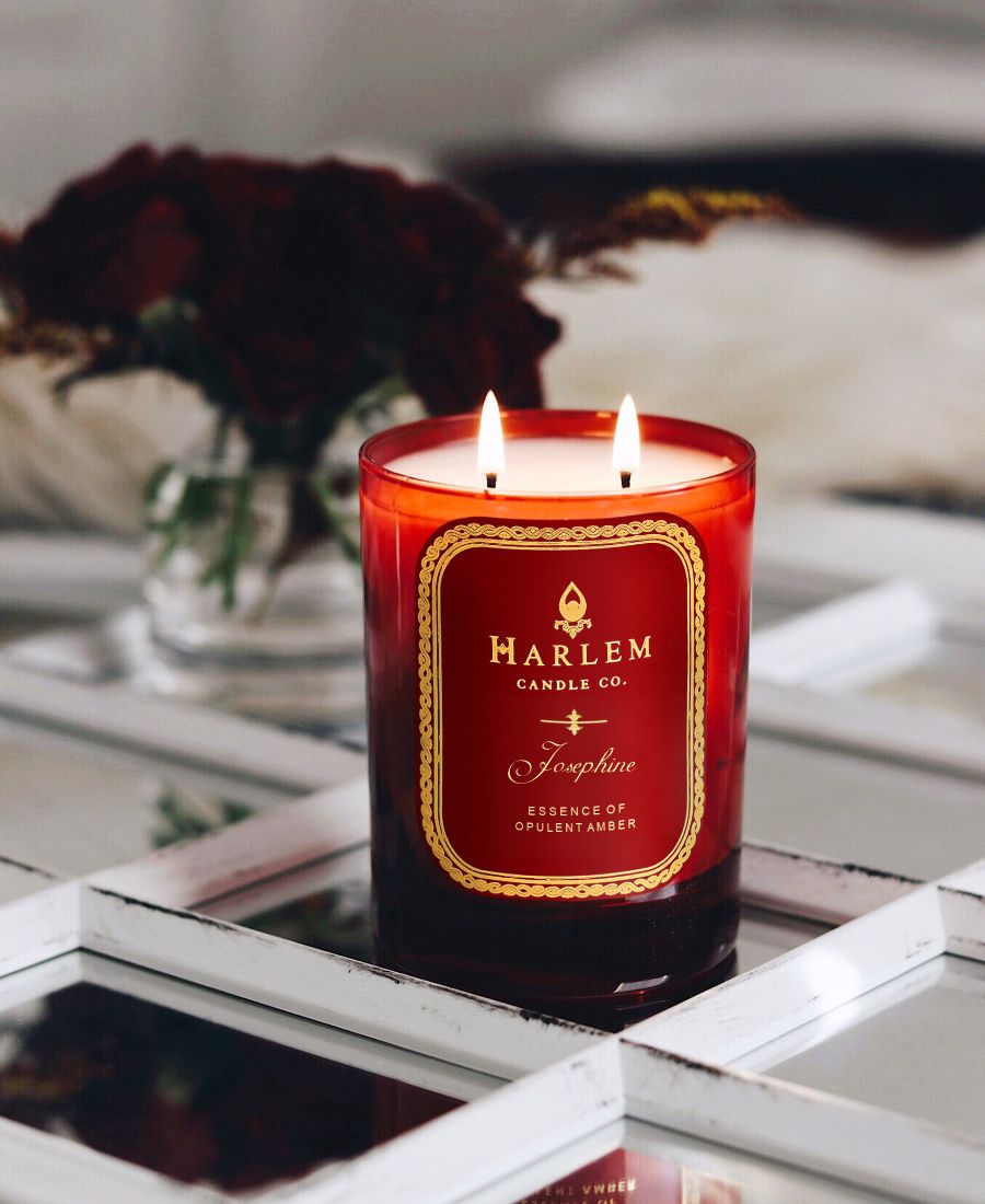 Red Josephine candle with Harlem Candle Co. label on a reflective surface.