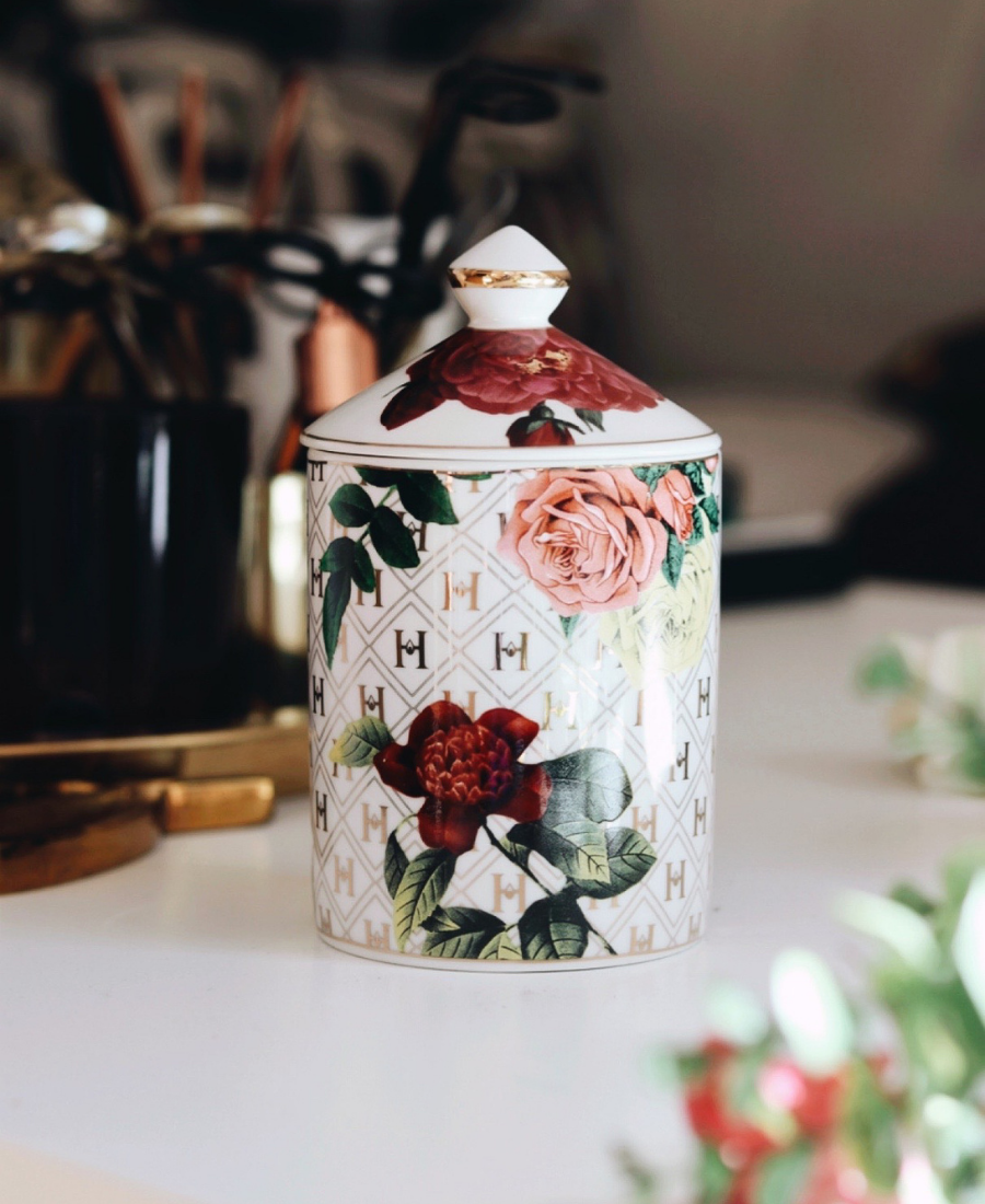 Lady Day Ceramic Candle on a white table with greenery and glassware and topped with the lid.