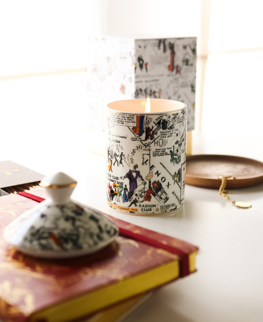Langston Ceramic Candle on a white table with box, candle lid, journals, wooden tray, matches, and jewelry.