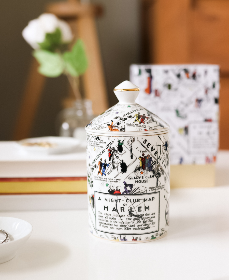 Langston Ceramic Candle topped with candle lid on a white table with box, flowers, journals, and ceramic dishes with jewelry.