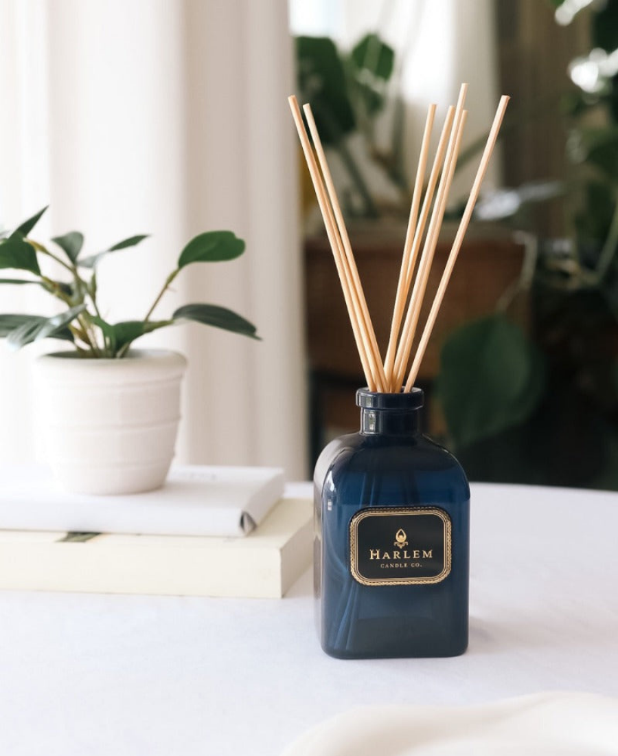 Langston Reed Diffuser on a white table with books and greenery.