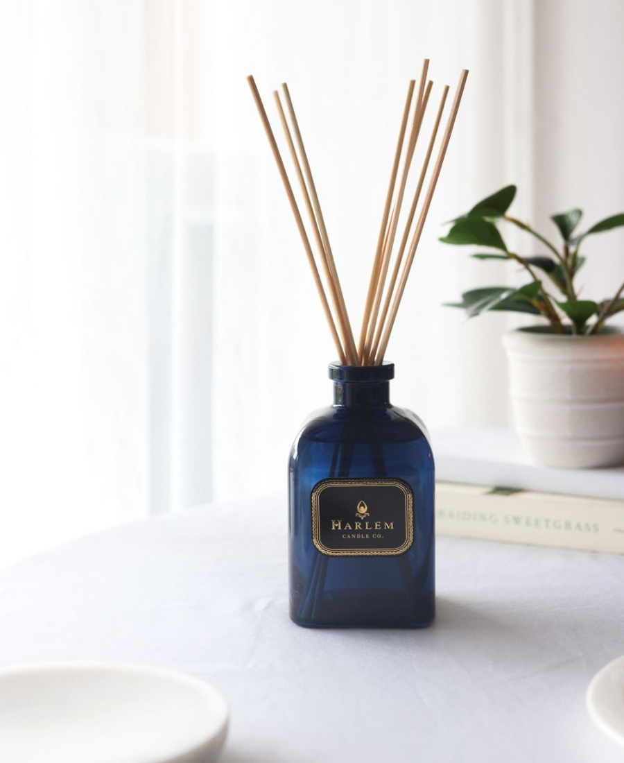 Langston Reed Diffuser on a white table with books and greenery.