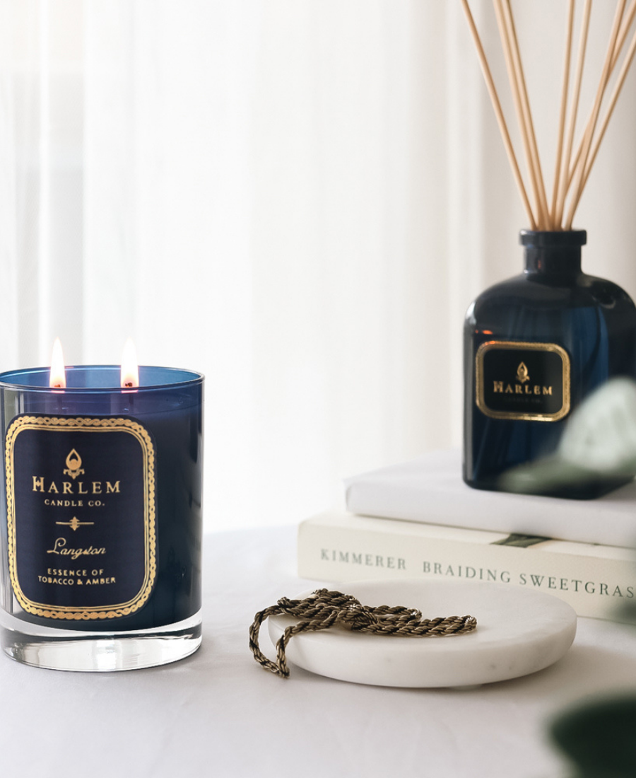 Langston Reed Diffuser on a white table with books, greenery, jewelry on a white tray, and the Langston Candle.
