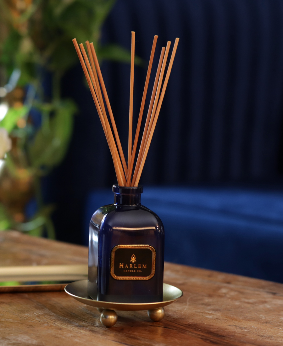 Langston Reed Diffuser on a wooden table with gold trays and greenery.