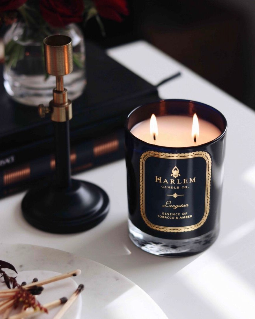 Langston Candle on a white table with books, a candle holder, and matches.
