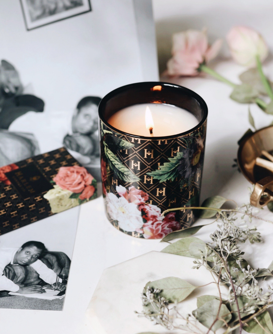 Love Ceramic Candle on a white table with flowers, a match box, and vintage photographs of James Baldwin.