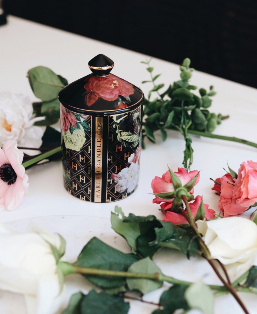 Love Ceramic Candle on a white table with flowers topped with the lid.