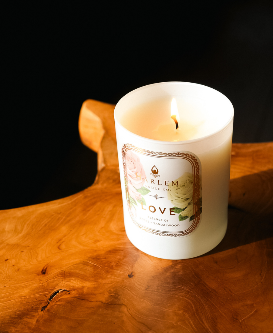 Love Candle on a natural wooden table with a black background.