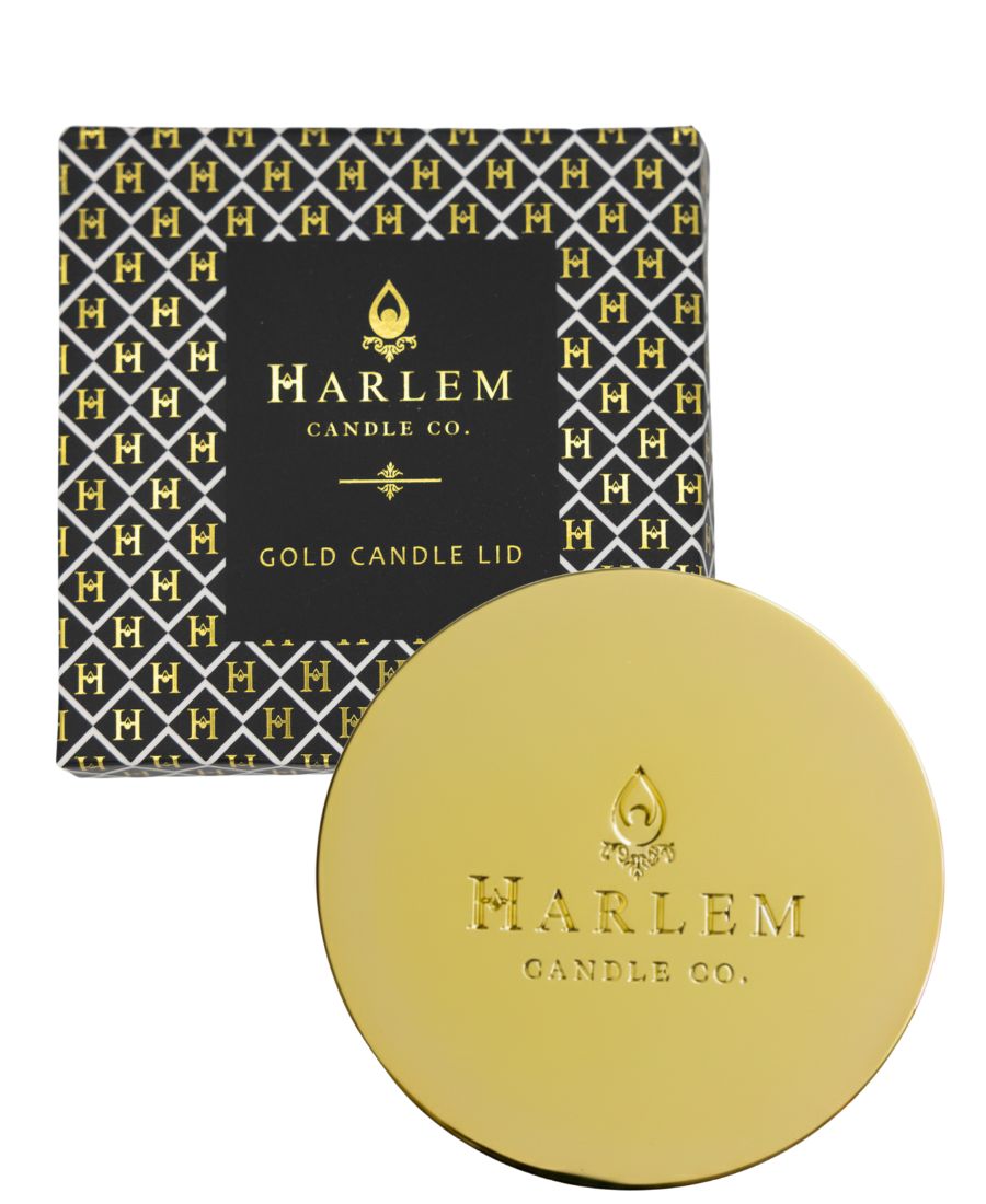 Gold candle lid with Harlem Candle Co. branding next to its packaging on a white background