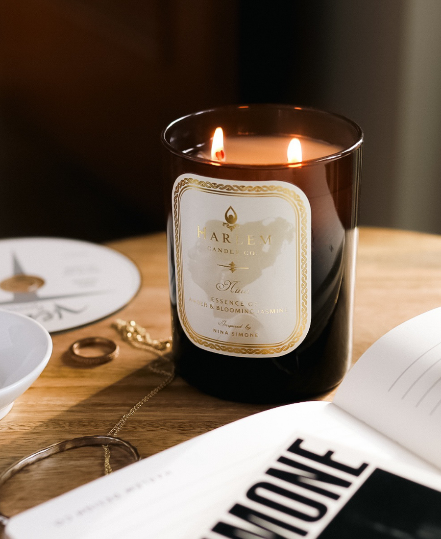 Nina Candle on a wooden table with jewelry and a Nina Simone CD and pamphlet.