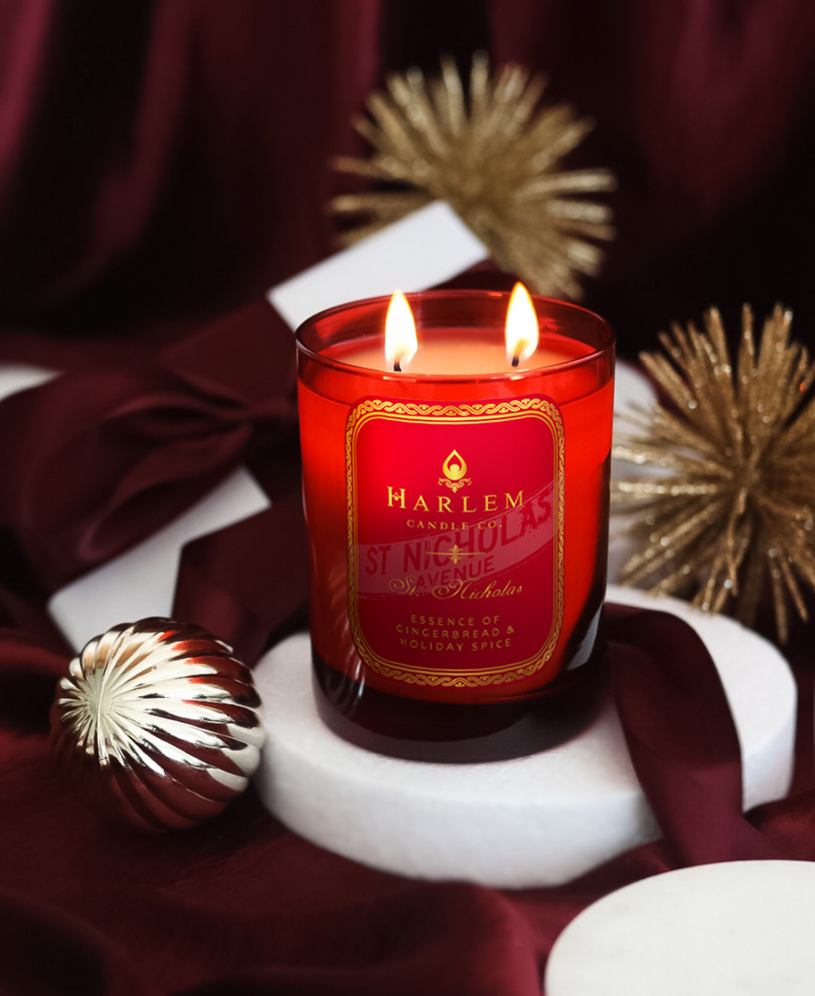 St. Nicholas candle on a white tray with maroon fabric with gold ornaments.