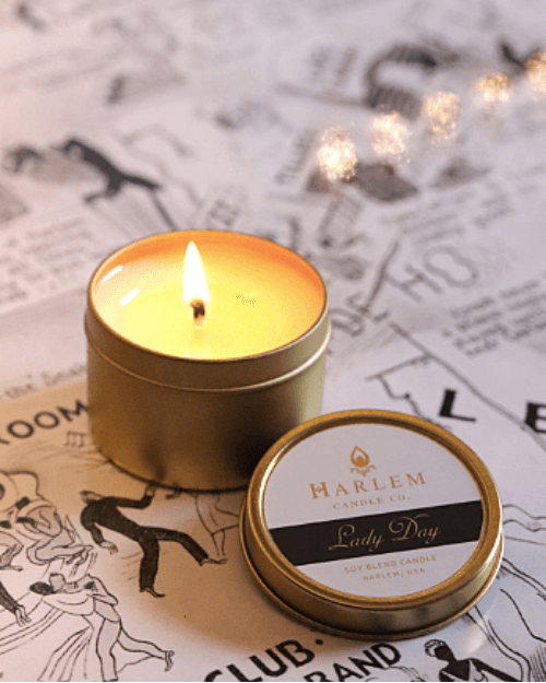 Gorgeous lifestyle image of the lit, 1 wick Lady Day 4 oz travel candle on top of a black and white harlem nightclub map.