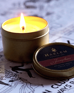 A lit Josephine 4 oz travel candle sitting on top of the black and white nightclub map of Harlem.