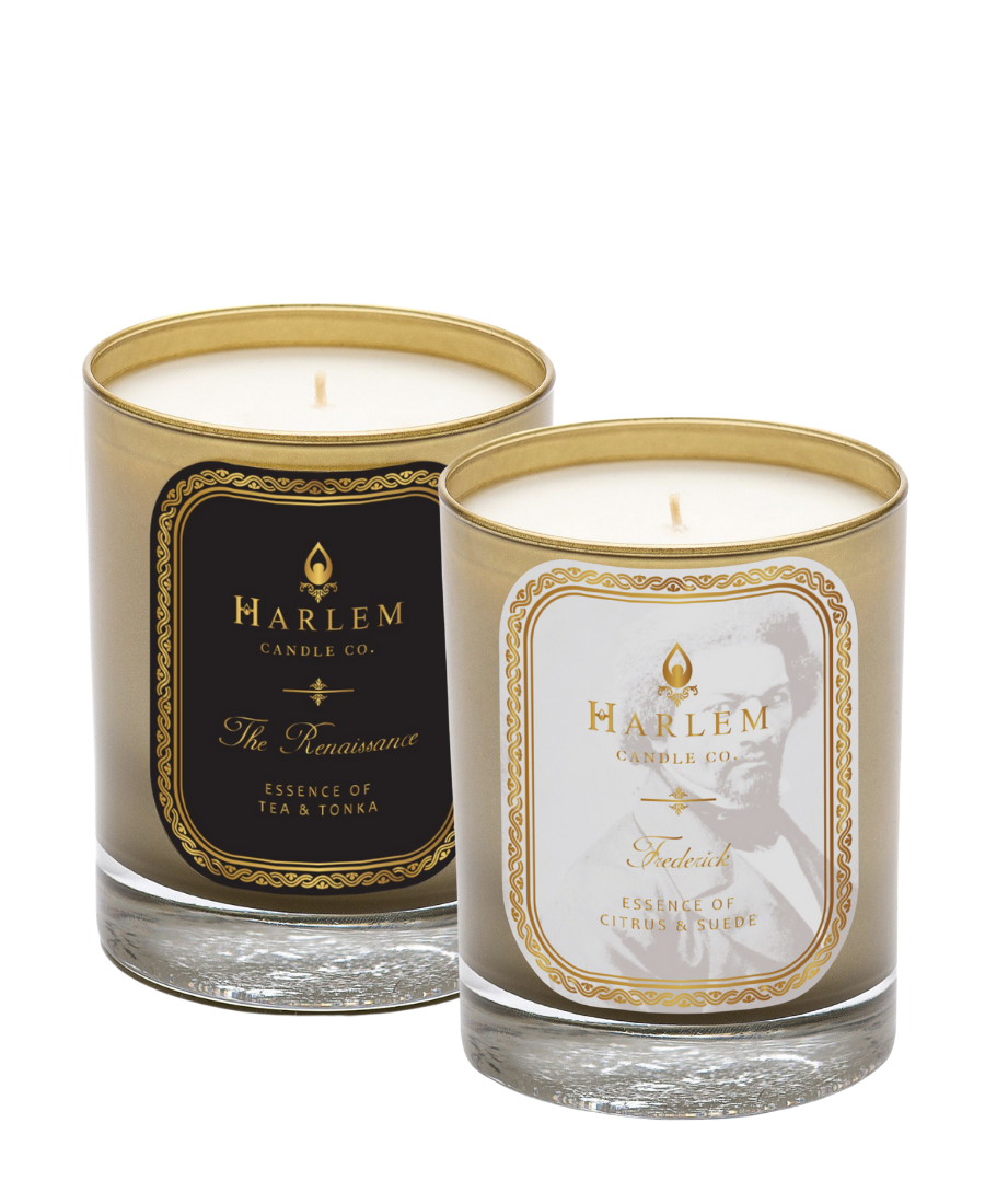 Two luxury candles in glass holders, one labeled 'Frederick' and the other 'Renaissance', with gold and black color schemes on the labels.