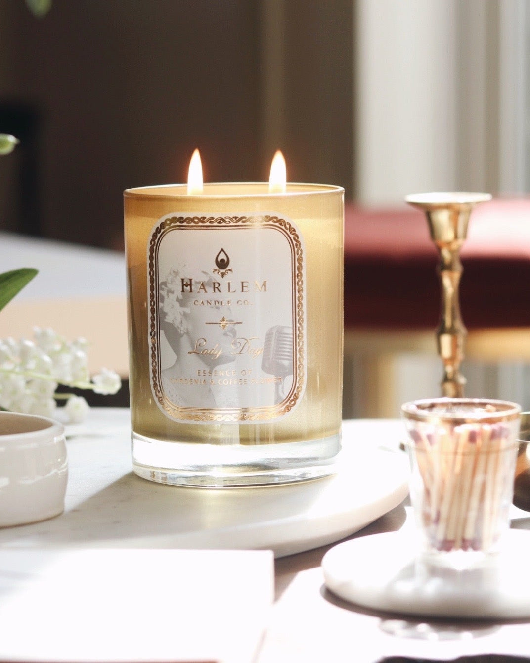 Lifestyle image of the Lady Day candle on a beautiful table with flowers.