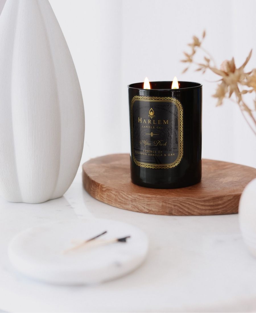 After Dark Candle on a wood tray with a white table and vase.