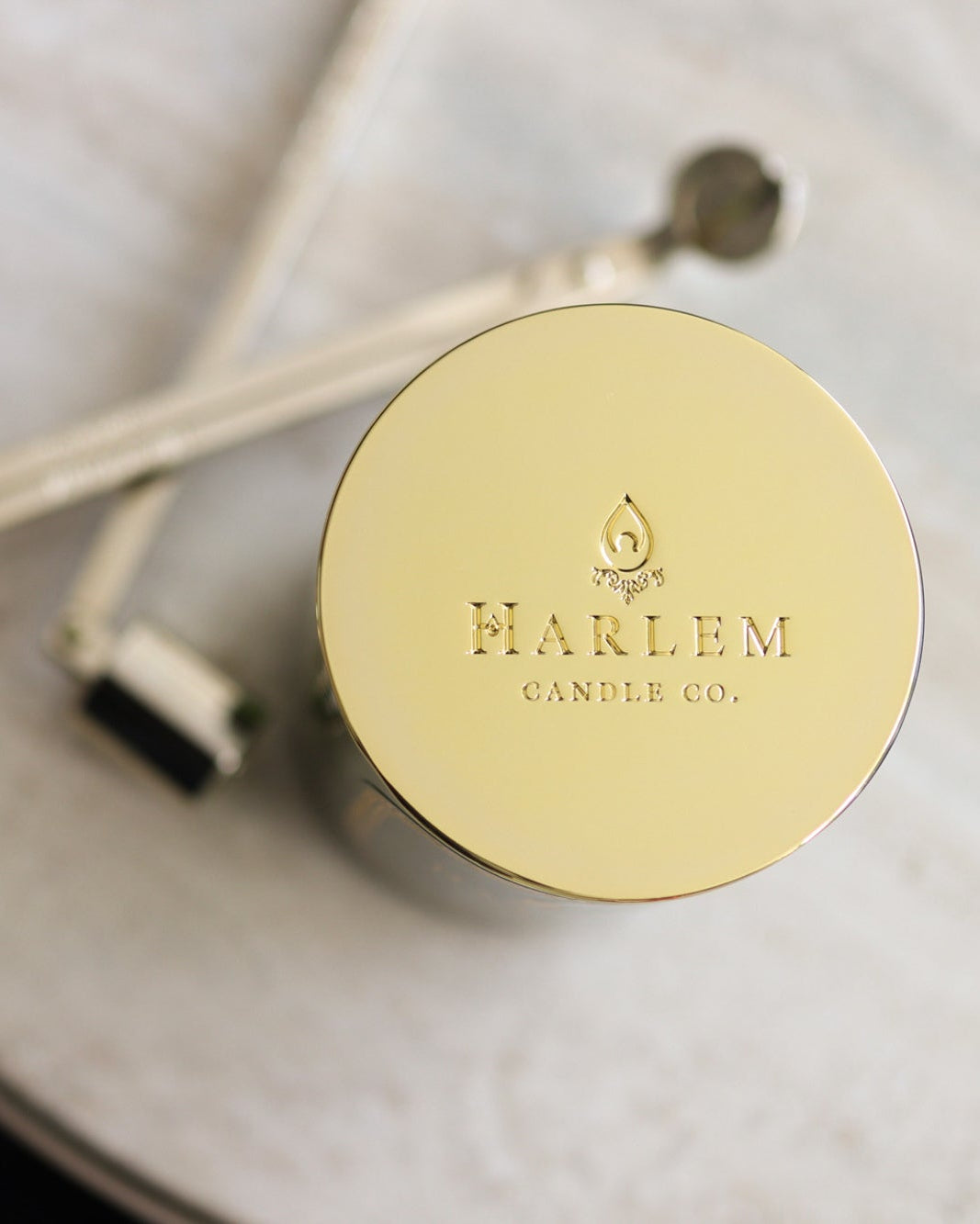 This is a different lifestyle image of our gold candle lid on our holiday candle pictured next to the wick trimmer and snuffer set.