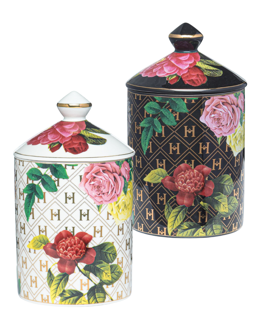 Two decorative lidded canisters with floral and monogram patterns, shown on a plain white background. One canister is white with a gold monogram lattice and pink/red flowers with green leaves.