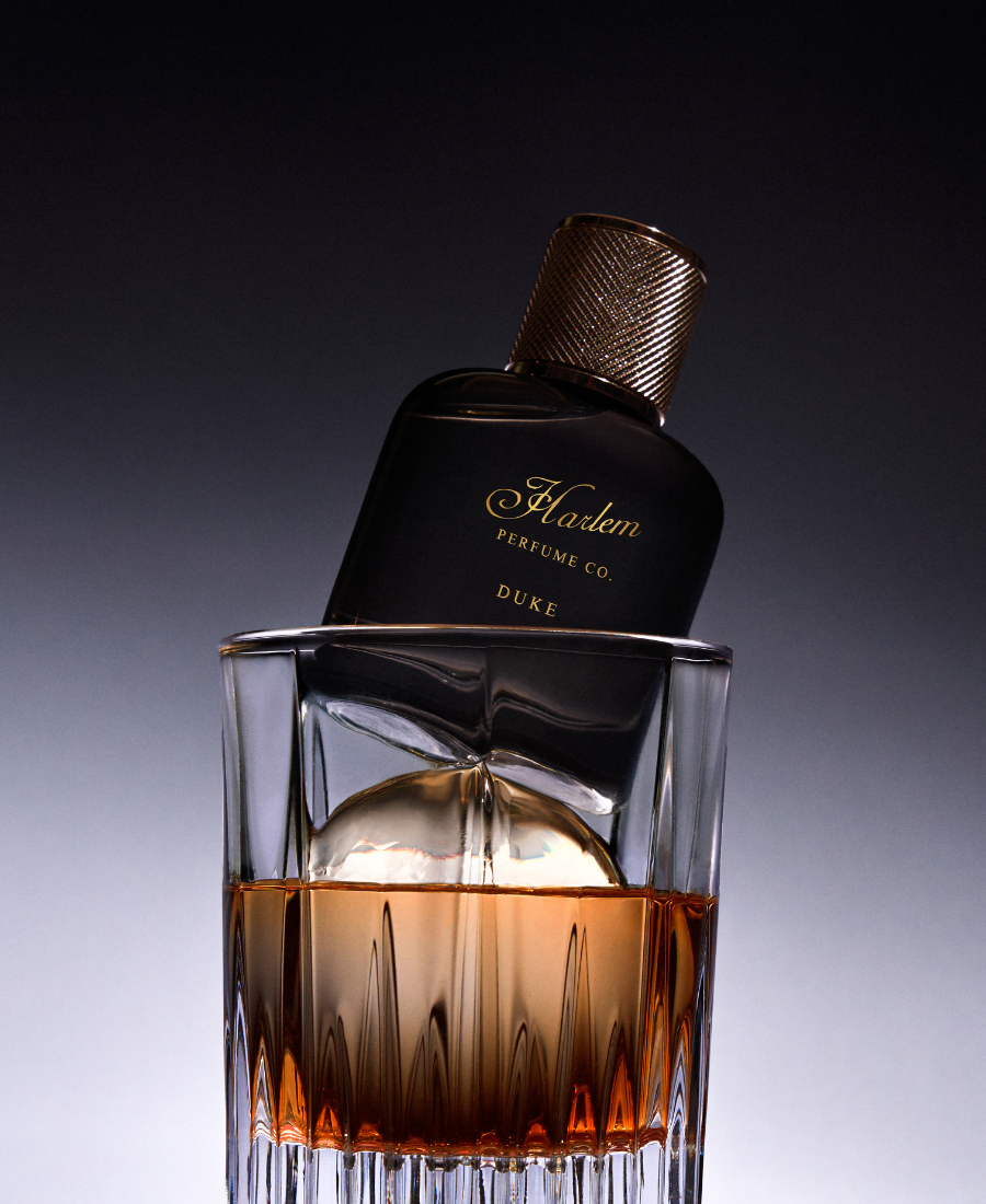 Harlem Perfume Co. Duke bottle with a glass of amber liquid on a gradient background