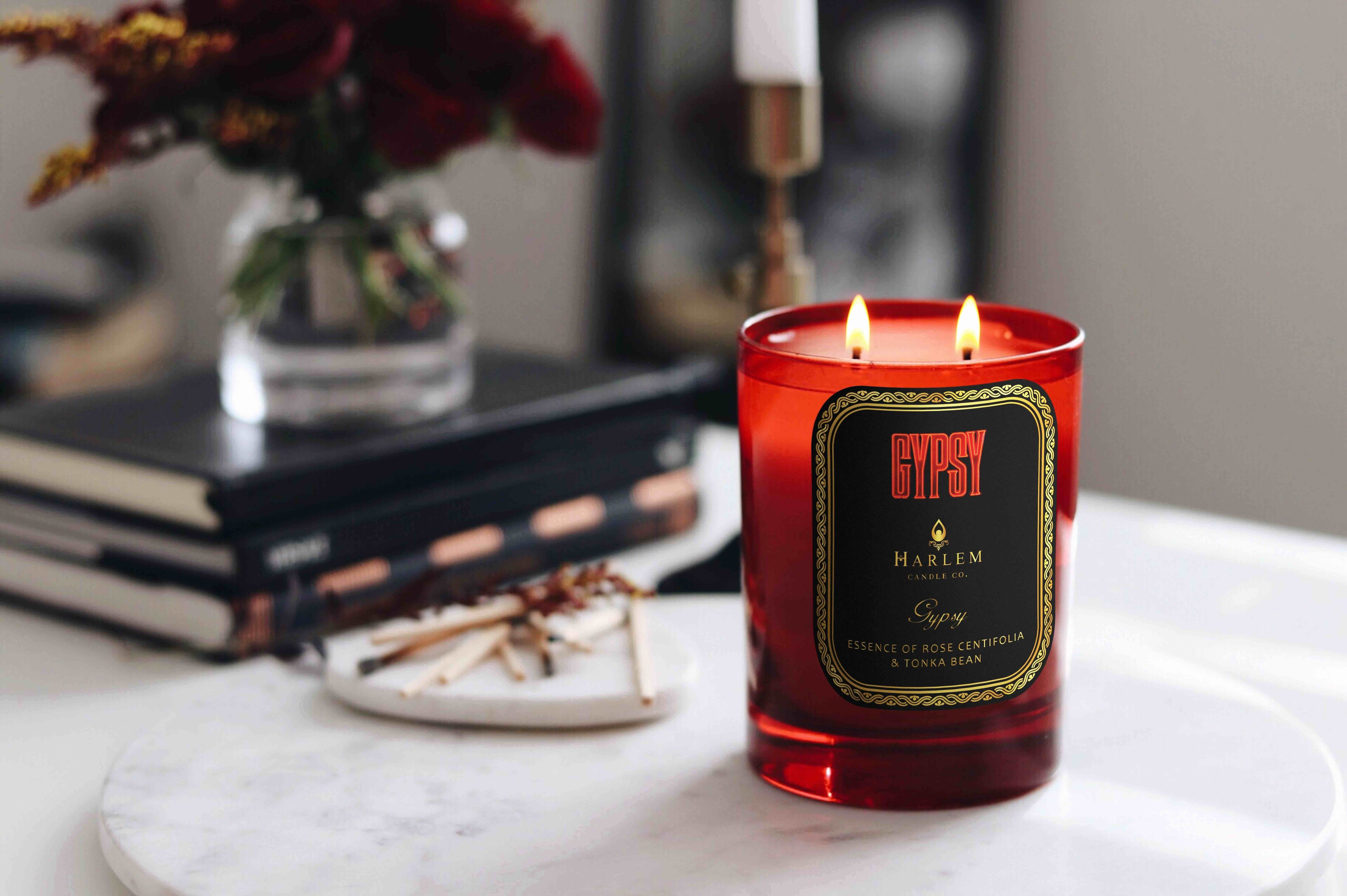 This is a lifestyle image of our gypsy candle with two weeks. It is featured with a bouquet of flowers in the background on a white marble circular table.