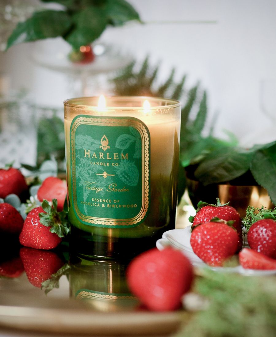 Harlem Candle Co. candle with strawberries on a reflective surface