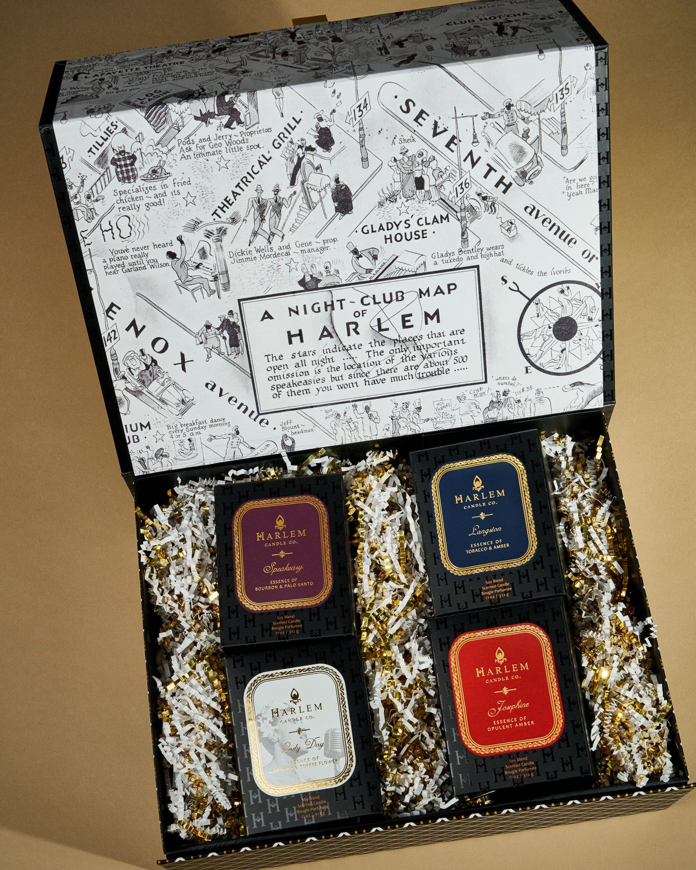 This is a lifestyle image of our Harlem, icons gift box with speakeasy, Langston, lady day, and Josephine inside of our custom gift box surrounded by gold and white crinkle paper.