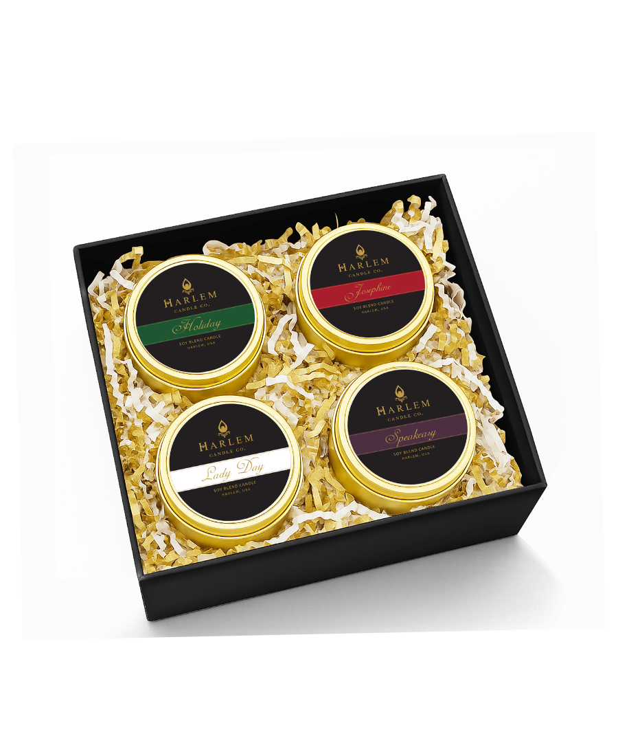 This is an image of our holiday travel candle set, which includes the holiday candle, the Josephine candle, the lady candle, and the speakeasy candle in black box with gold and white crinkle paper.