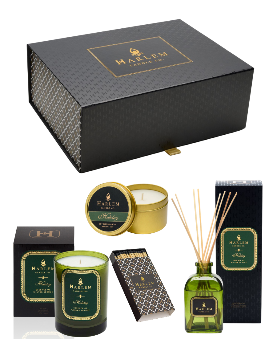 Our gorgeous custom Harlem Candle Co black gift box with the H pattern with the images of our Holiday 12 oz 1 wick candle, our 4 oz Holiday Travel Tin, our 4 fl oz and our green glass Holiday Reed Diffuser sitting next to its decorative box.