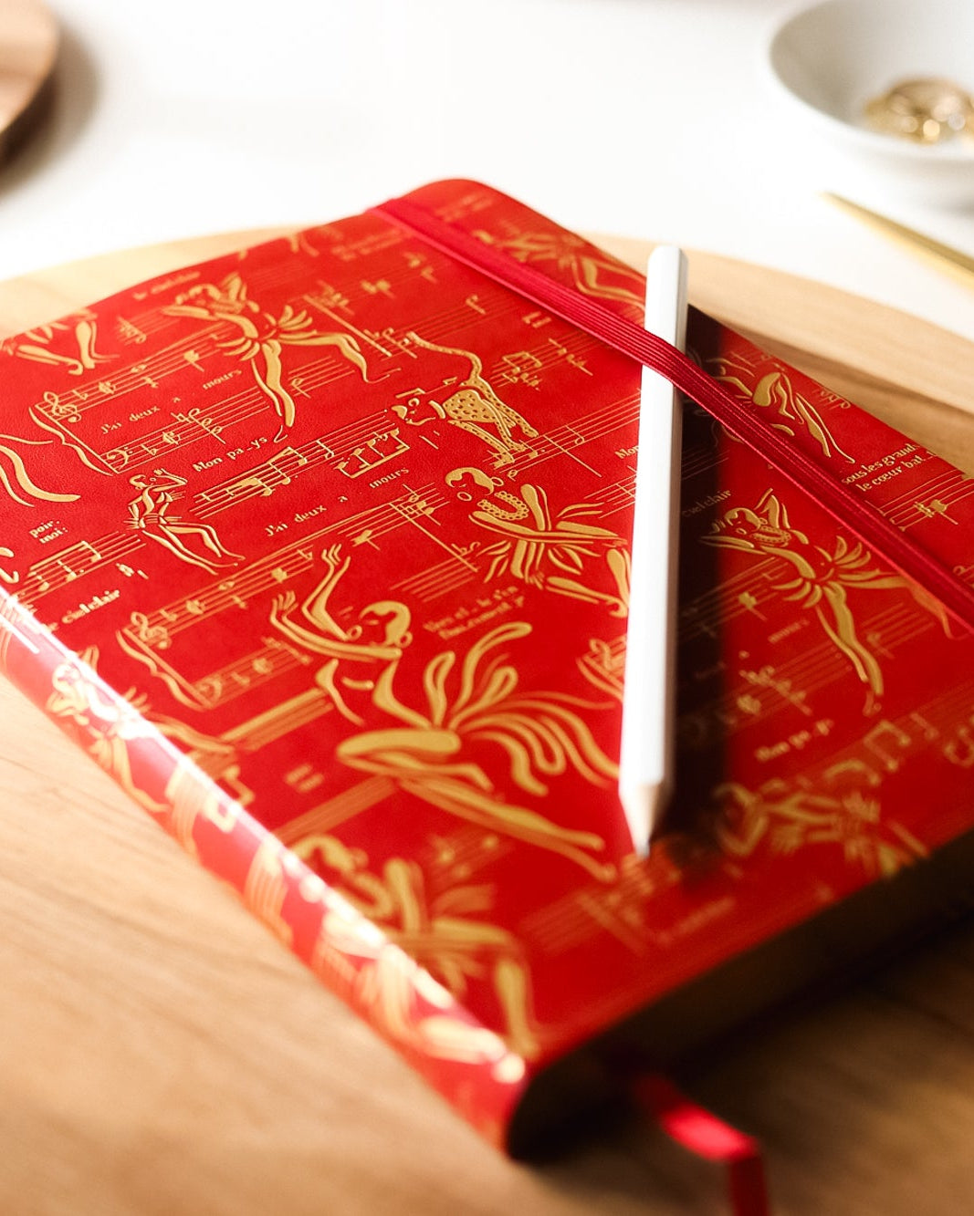 The red journal on a table with a pencil.