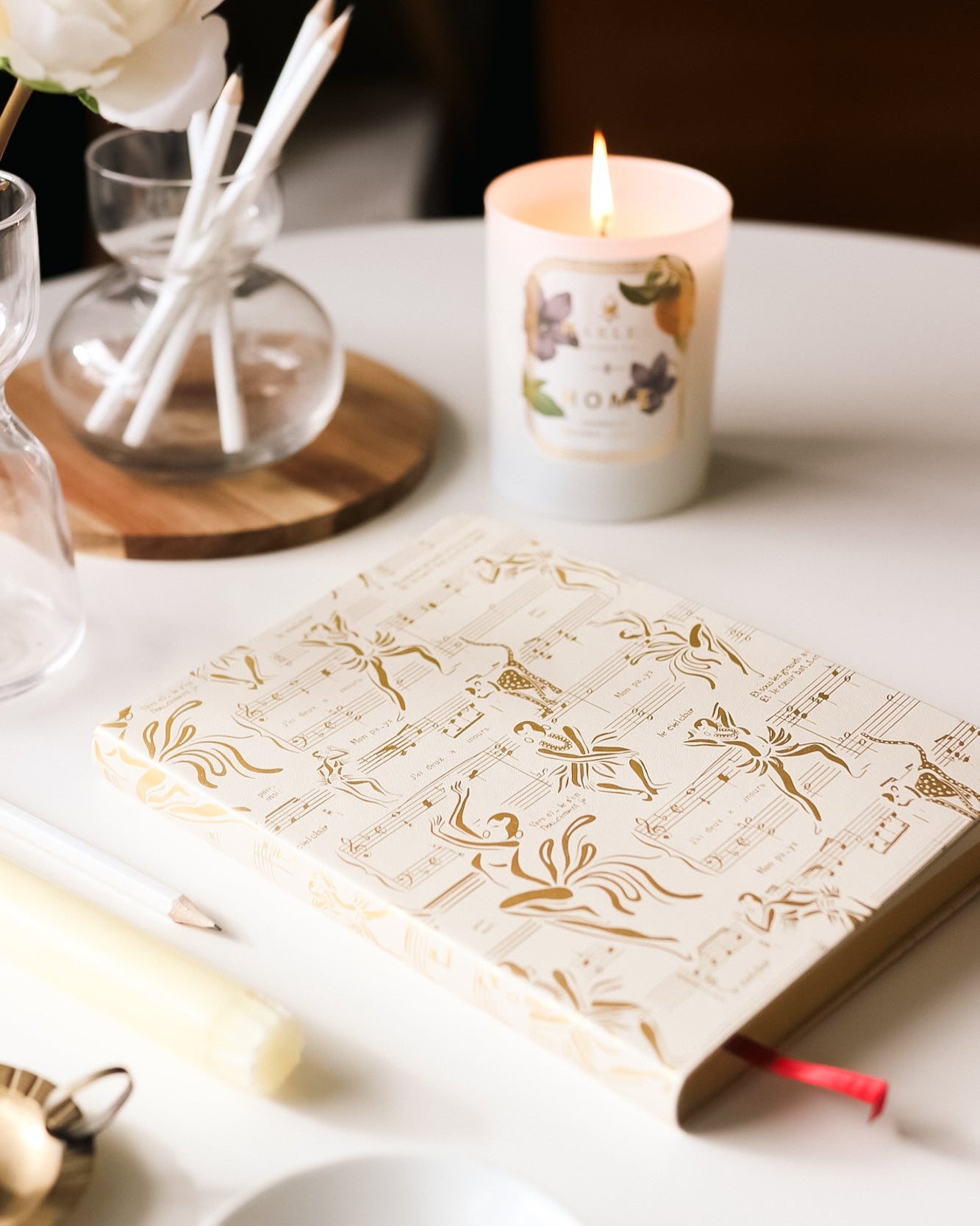 This is an image of our Josephine journal and cream and gold pictured next to our home candle with the flame illuminated.