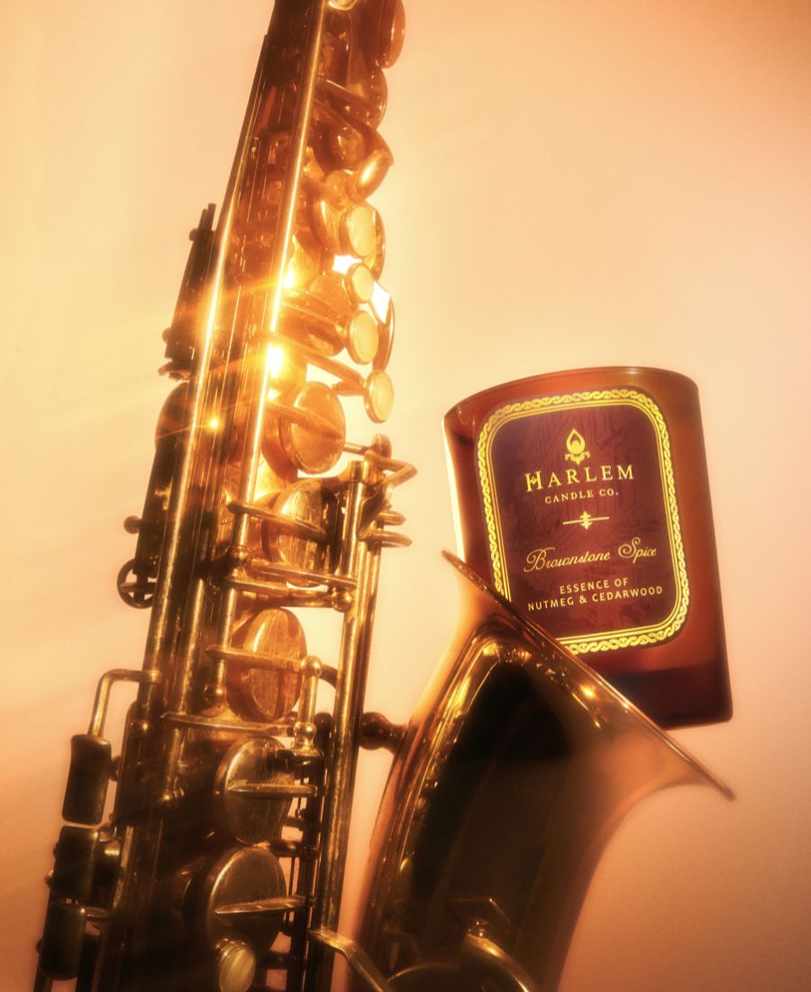 Gold saxophone next to a Harlem Candle Co candle on a light background