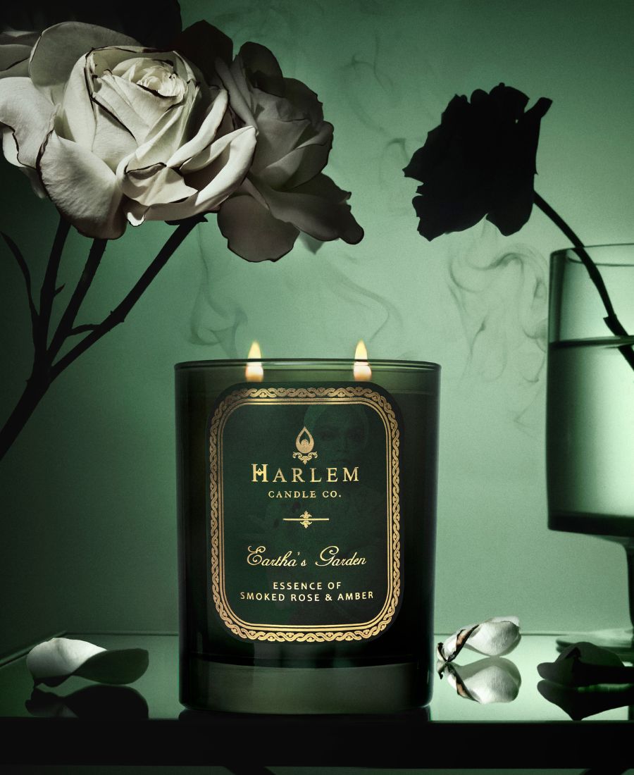 Eartha's Garden candle in a green glass with green label with an image of Eartha Kitt in the background.  In a lifestyle setting.
